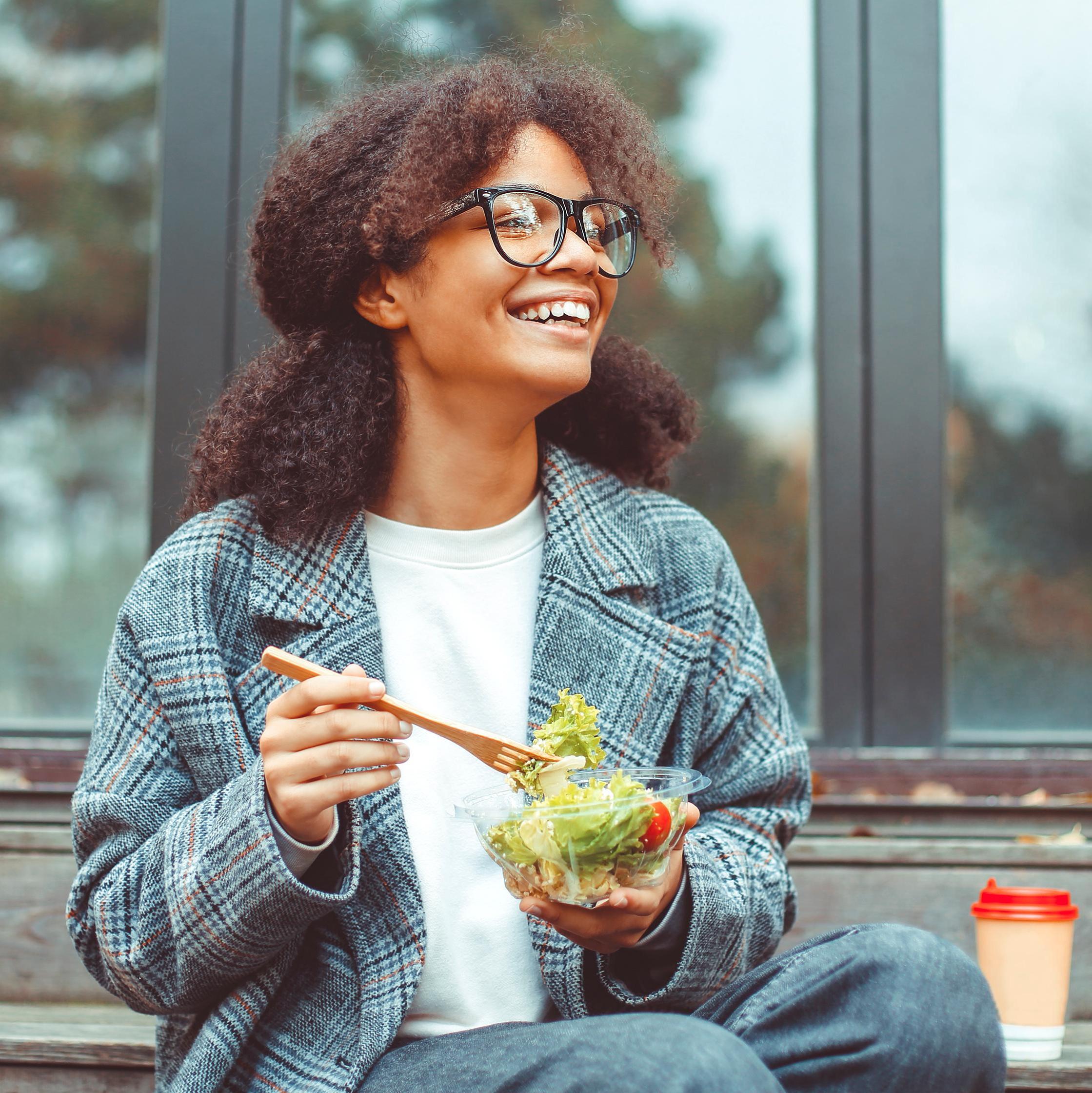 happy african american woman office worker smiling while eating a salad