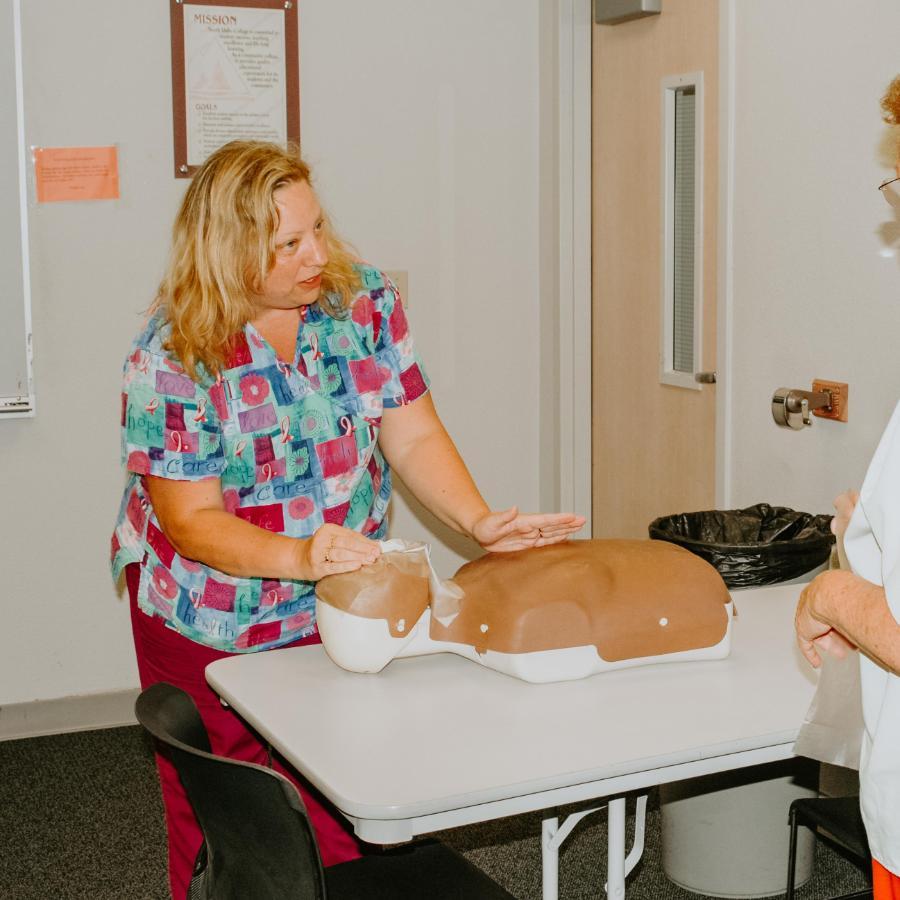 900x900 Female CNA Student working a dummy with an instructor