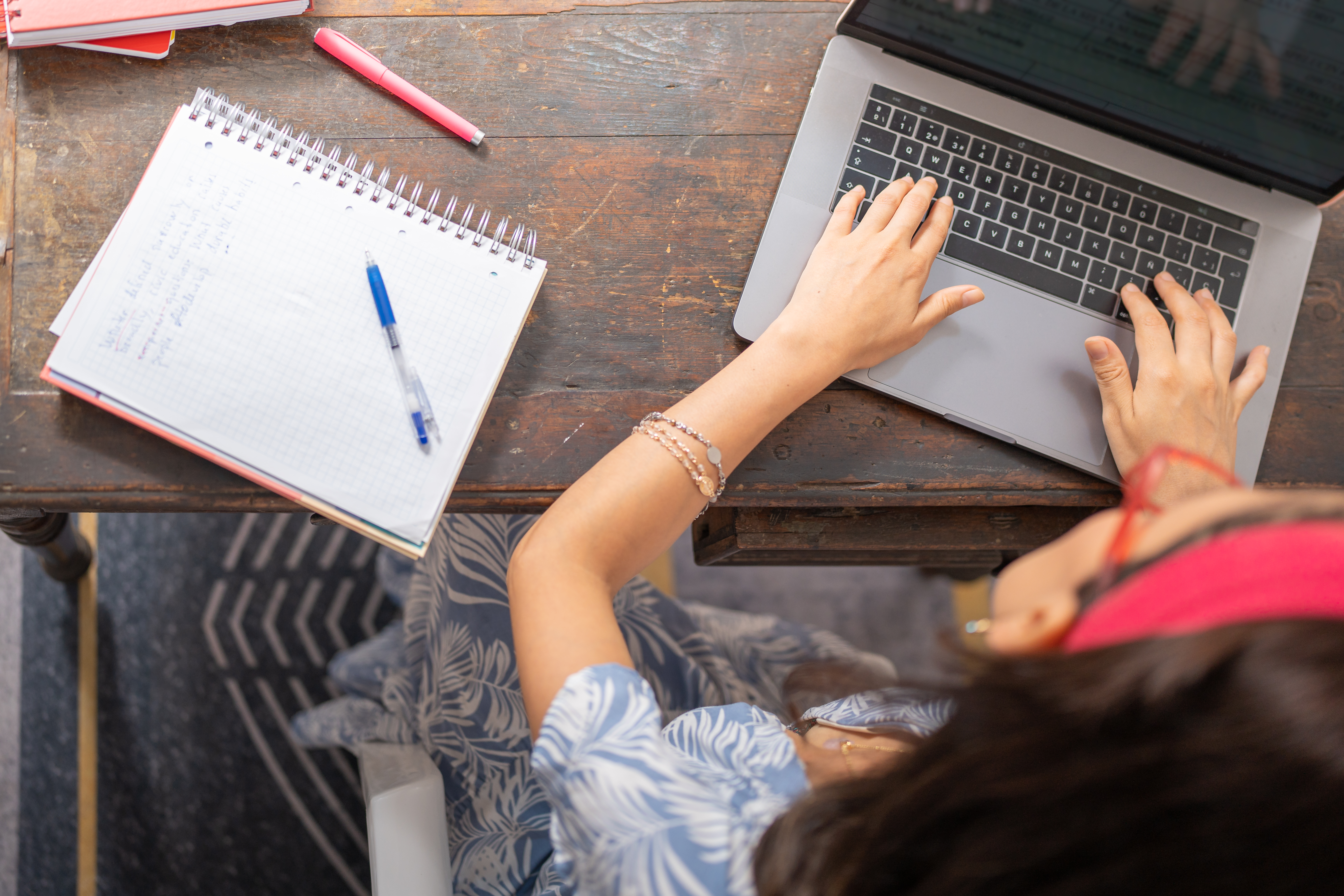 top view looking down on Female student typing on a computer at desk with notes