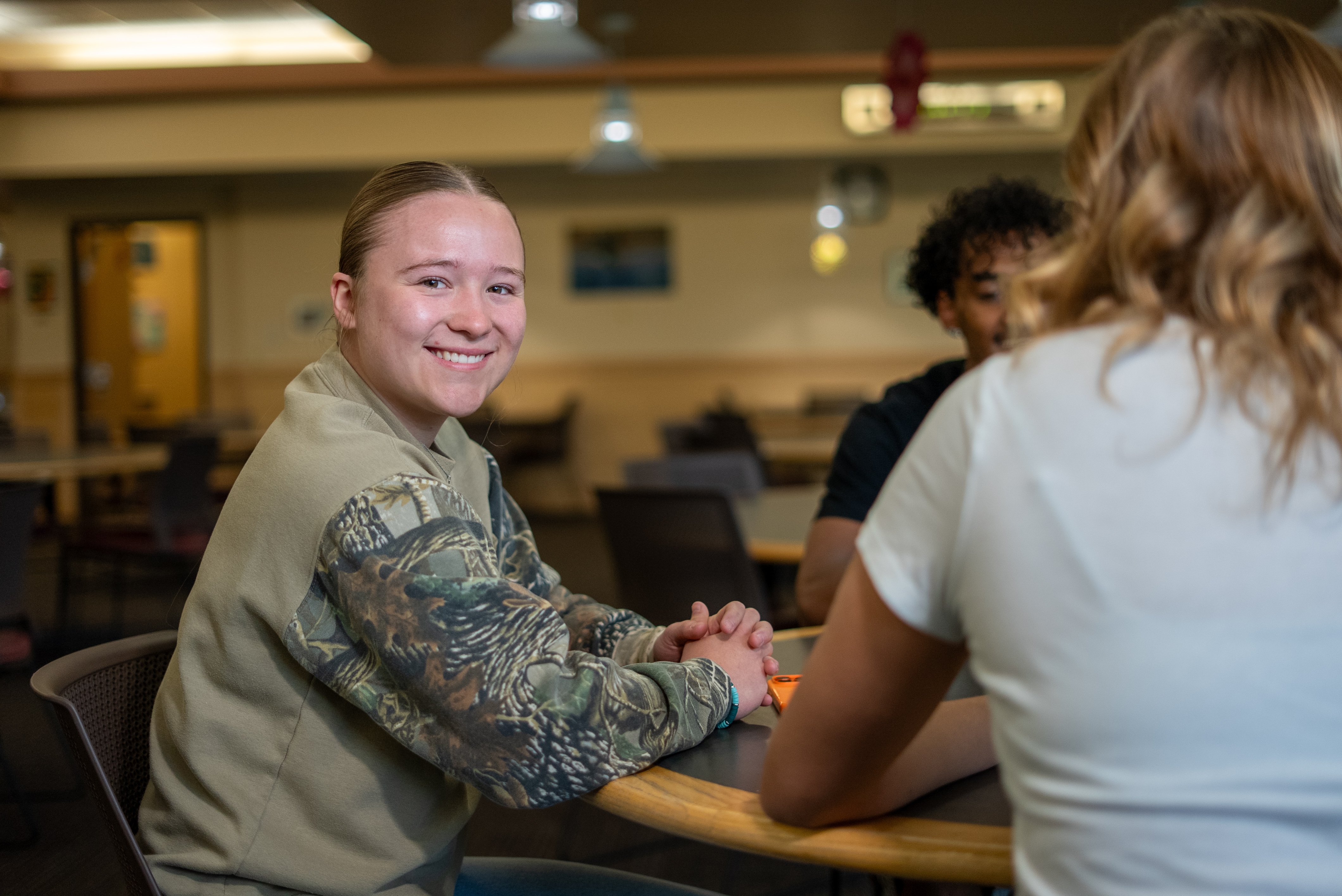 female smiling sitting with Students at a table