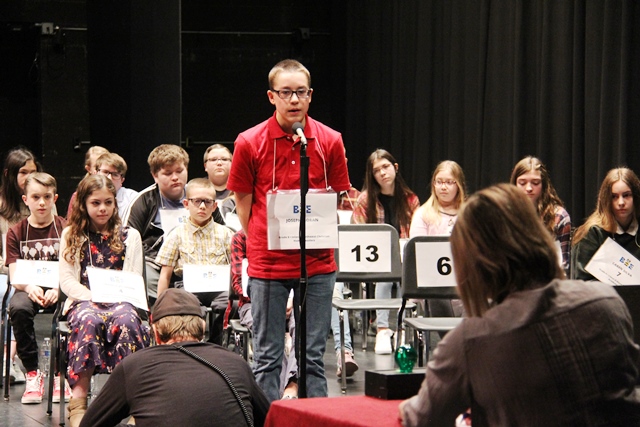 Spelling bee winner Joseph Moran standing in front of the judges