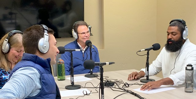 President and others in front of microphone during the podcast production