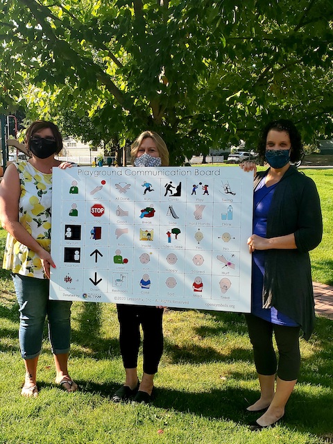 People pose with a large children's communication board