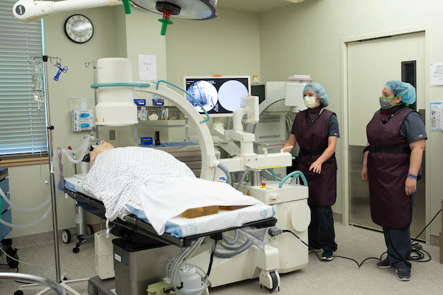 Radiography students beside a Radiography C-Arm