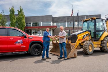 NIC Executive Director of Workforce and Economic Development Colby Mattila, left, receives the keys to a 2020 Caterpillar 420E loader backhoe from ACI Northwest, Inc. President and CEO Bill Radobenko on Wednesday, July 22 and the NIC Parker Technical Education Center in Rathdrum.