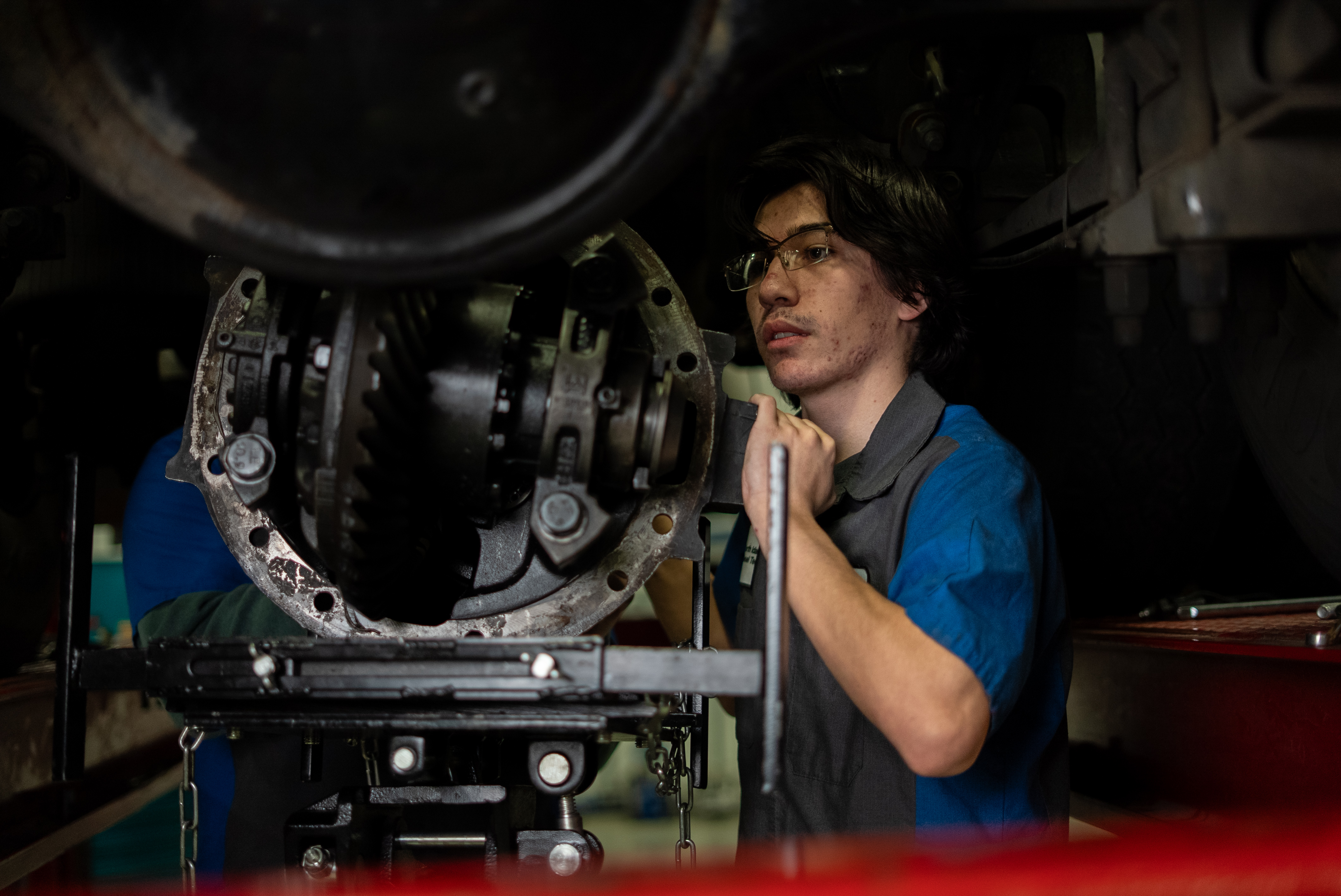  male Diesel Tech Student fixing hardware under lifted truck