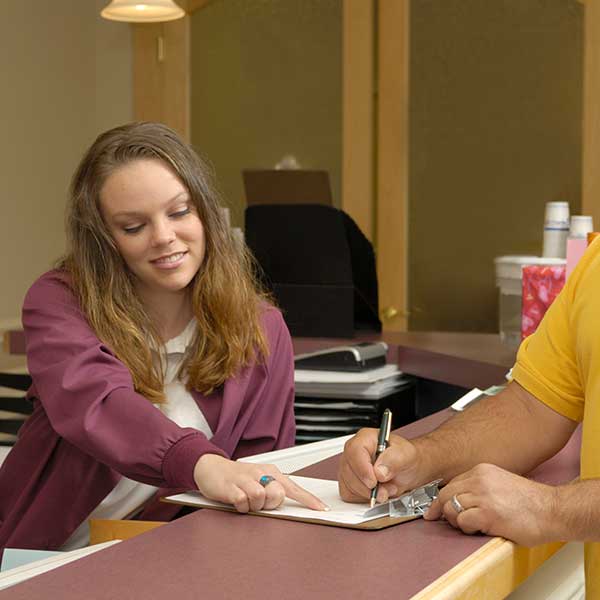 Medical Receptionist helping a patient at the front desk