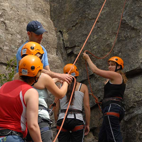 Outdoor recreational leader helping students learn rock climbing
