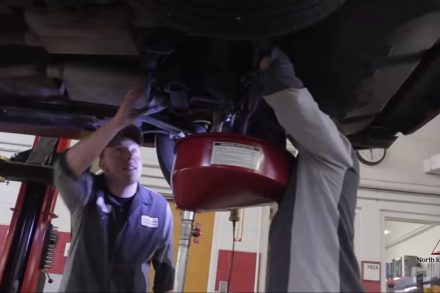 Students examine the underside of a car